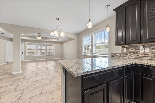 kitchen featuring ceiling fan with notable chandelier, decorative light fixtures, tasteful backsplash, and light stone countertops