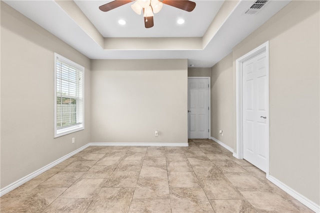 unfurnished bedroom with ceiling fan and a tray ceiling