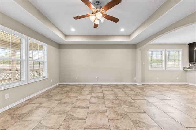 spare room featuring a wealth of natural light, ceiling fan, and a raised ceiling