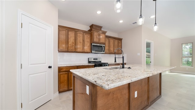 kitchen featuring backsplash, stainless steel appliances, sink, pendant lighting, and an island with sink