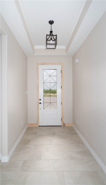 doorway with ornamental molding and a tray ceiling