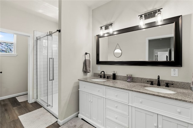 964 Allende St, Seguin, TX 78155 - bathroom with wood finished floors, a shower stall, double vanity, and baseboards