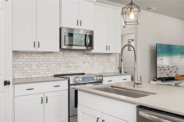 964 Allende St, Seguin, TX 78155 - kitchen with appliances with stainless steel finishes, light countertops, a sink, white cabinets, and decorative backsplash