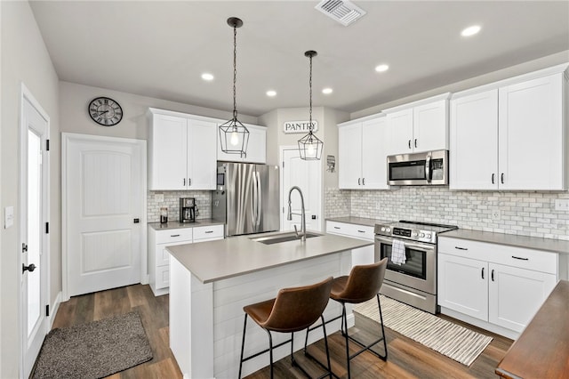 964 Allende St, Seguin, TX 78155 - kitchen featuring stainless steel appliances, a sink, dark wood-style flooring, a kitchen island with sink, and decorative backsplash