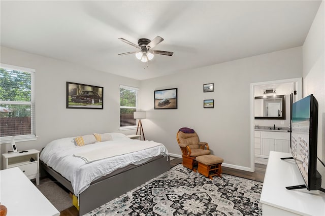 964 Allende St, Seguin, TX 78155 - bedroom with dark wood-style flooring, baseboards, ensuite bath, and ceiling fan