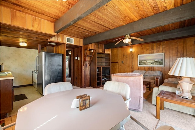 carpeted dining area with sink, wood walls, wooden ceiling, ceiling fan, and beam ceiling