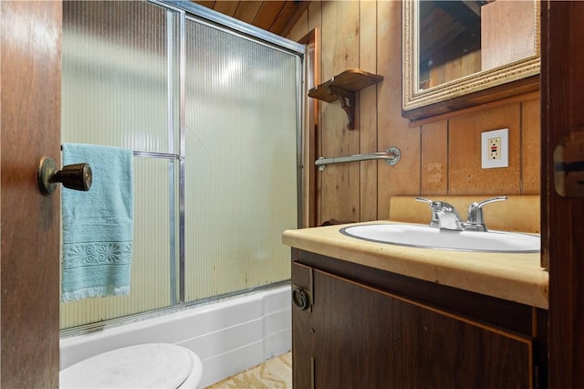 full bathroom with toilet, vanity, bath / shower combo with glass door, and wood walls