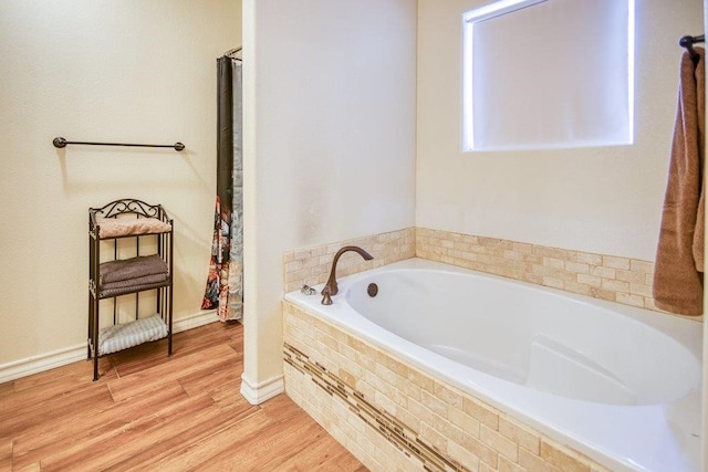 2421 Country Oaks Cir, Ingleside, TX 78362 - bathroom featuring a garden tub, baseboards, and wood finished floors