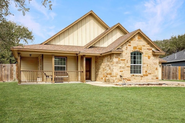 view of front of home featuring stone siding, fence, board and batten siding, and a front yard