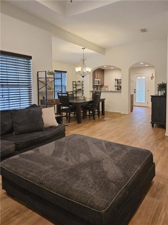 2421 Country Oaks Cir, Ingleside, TX 78362 - living area featuring arched walkways, visible vents, light wood-style flooring, and an inviting chandelier