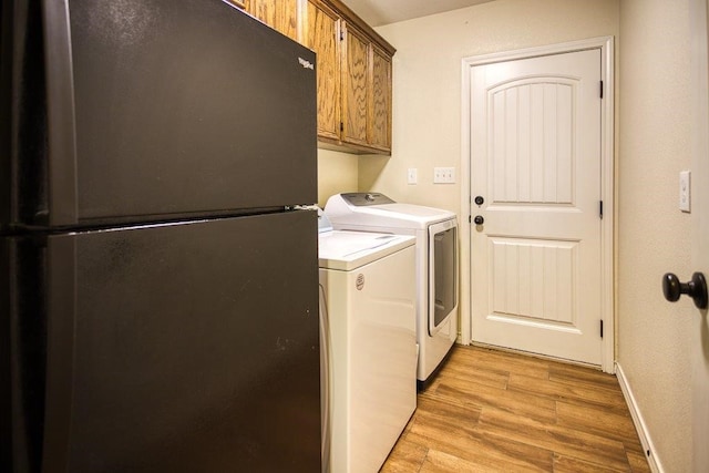 2421 Country Oaks Cir, Ingleside, TX 78362 - laundry area featuring cabinet space, washing machine and dryer, baseboards, and light wood-style flooring