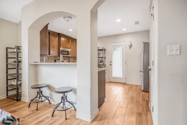 2421 Country Oaks Cir, Ingleside, TX 78362 - kitchen with arched walkways, stainless steel appliances, light wood finished floors, and decorative backsplash