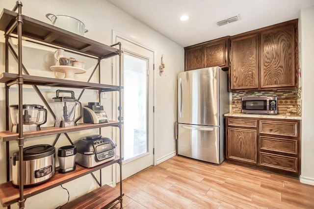 2421 Country Oaks Cir, Ingleside, TX 78362 - kitchen with visible vents, a healthy amount of sunlight, appliances with stainless steel finishes, backsplash, and light wood finished floors