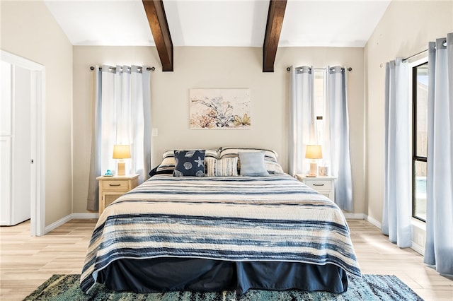 bedroom featuring beam ceiling, baseboards, and light wood-style flooring