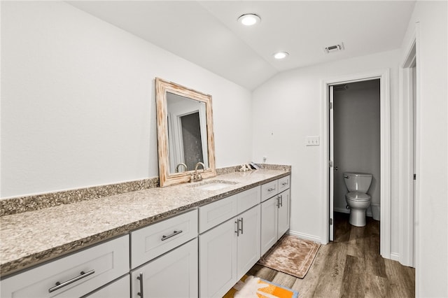 bathroom with toilet, wood finished floors, visible vents, lofted ceiling, and vanity