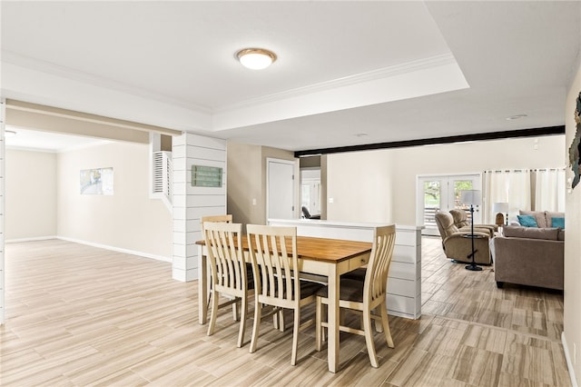 dining area featuring crown molding, light wood-style flooring, and a raised ceiling