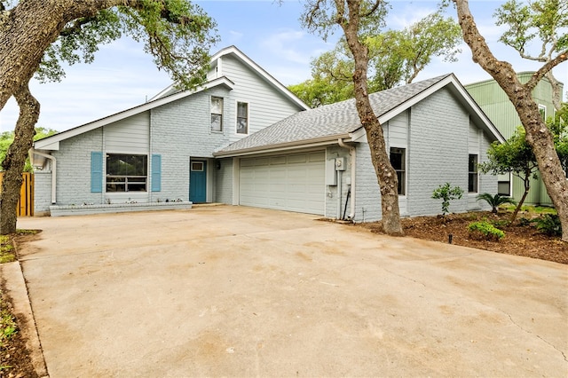 view of front of home featuring an attached garage, concrete driveway, brick siding, and roof with shingles