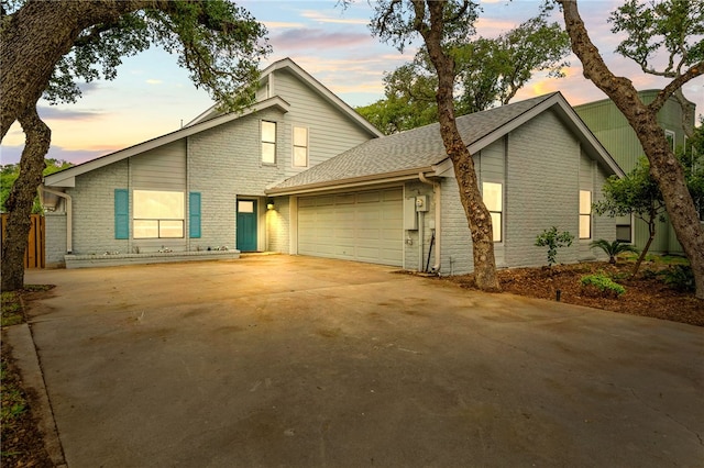 view of front of property featuring roof with shingles, concrete driveway, an attached garage, and brick siding