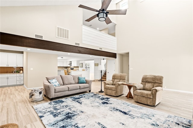living room featuring a high ceiling, visible vents, baseboards, and ceiling fan