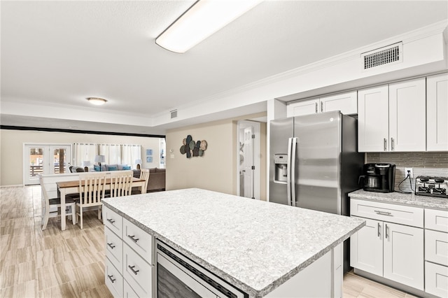 kitchen featuring a kitchen island, crown molding, light countertops, and visible vents