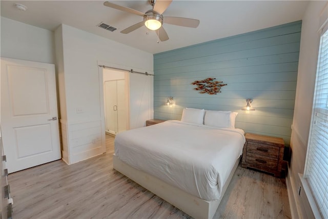 129 N Alister St Unit 2, Port Aransas, TX 78373 - bedroom featuring light wood-style flooring, a barn door, wood walls, and ceiling fan