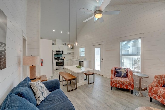 129 N Alister St Unit 2, Port Aransas, TX 78373 - living room with high vaulted ceiling, light wood-type flooring, wood walls, and ceiling fan