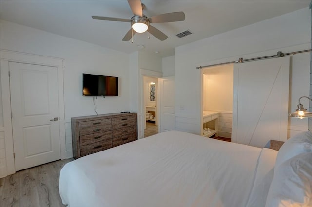 129 N Alister St Unit 2, Port Aransas, TX 78373 - bedroom with wood finished floors, a barn door, ceiling fan, and ensuite bathroom