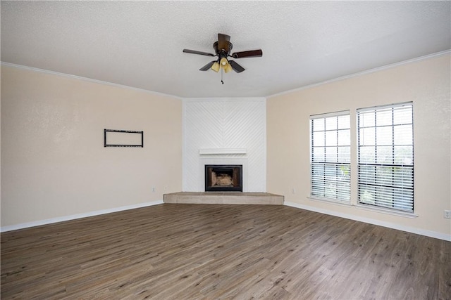 unfurnished living room with ornamental molding, a textured ceiling, a large fireplace, ceiling fan, and dark hardwood / wood-style floors