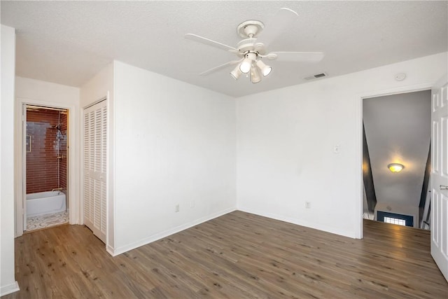 unfurnished bedroom featuring dark hardwood / wood-style flooring, ceiling fan, a closet, and a textured ceiling