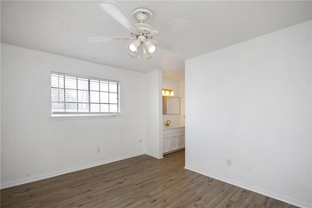 unfurnished room with ceiling fan, sink, and dark wood-type flooring