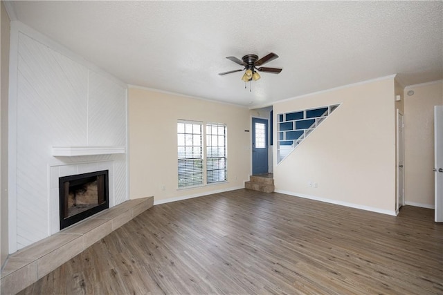 unfurnished living room with a textured ceiling, ceiling fan, crown molding, wood-type flooring, and a fireplace