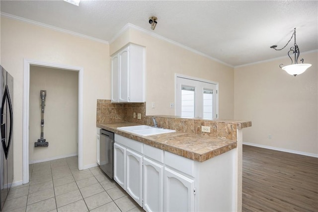 kitchen with sink, kitchen peninsula, decorative light fixtures, white cabinets, and appliances with stainless steel finishes