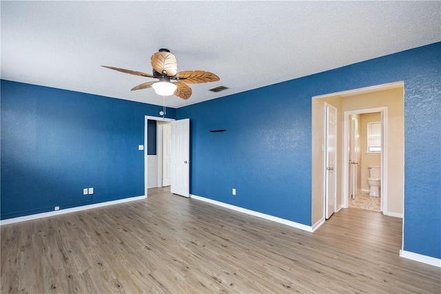 empty room featuring a textured ceiling, light wood-type flooring, and ceiling fan