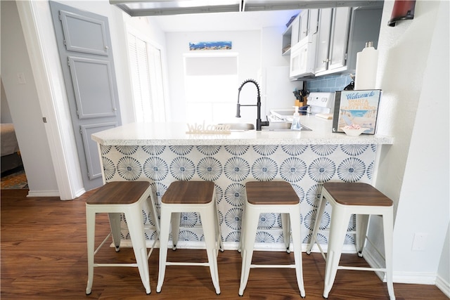 kitchen with dark wood-type flooring, white electric stove, a breakfast bar, and kitchen peninsula