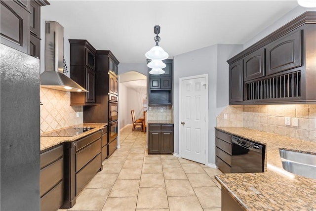 kitchen featuring light stone counters, arched walkways, wall chimney exhaust hood, decorative backsplash, and black appliances