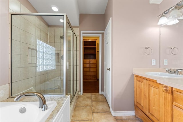 full bath featuring a garden tub, a shower stall, vanity, tile patterned floors, and a spacious closet