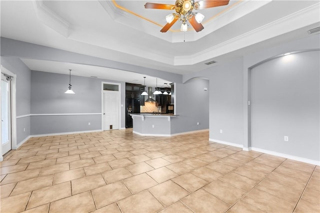 unfurnished living room with arched walkways, a raised ceiling, ceiling fan, and light tile patterned floors