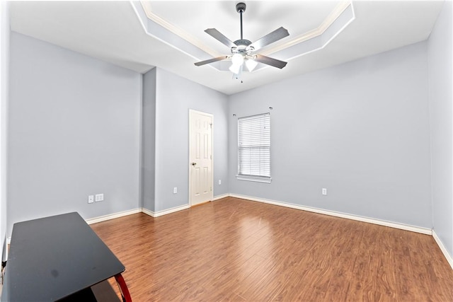 unfurnished room with a ceiling fan, baseboards, wood finished floors, and a raised ceiling