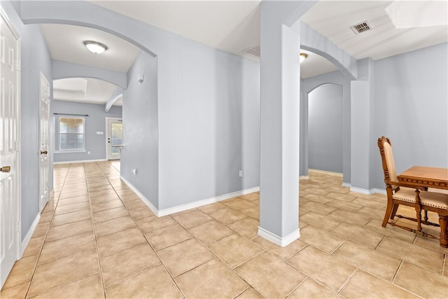 interior space with arched walkways, baseboards, visible vents, and light tile patterned floors