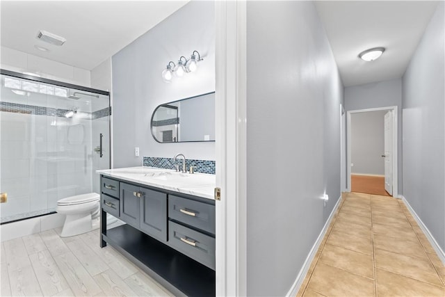 bathroom featuring vanity, toilet, baseboards, visible vents, and a stall shower
