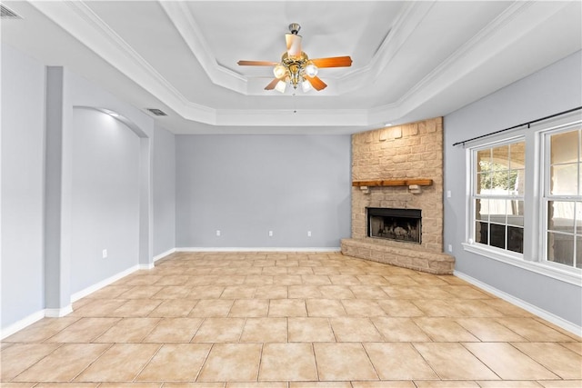 unfurnished living room with crown molding, a raised ceiling, a stone fireplace, a ceiling fan, and light tile patterned floors