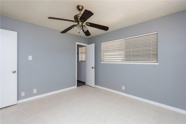 spare room featuring a ceiling fan and baseboards