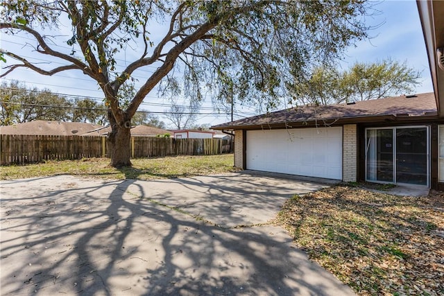 exterior space featuring a garage, driveway, and fence