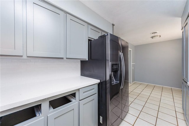 kitchen with stainless steel fridge, light countertops, light tile patterned floors, and tasteful backsplash