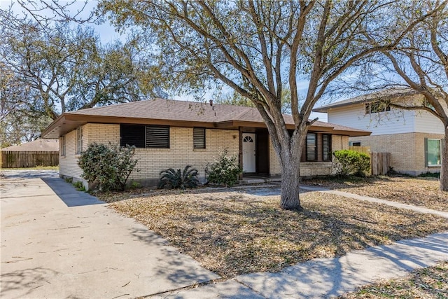 ranch-style house with brick siding, concrete driveway, and fence