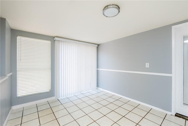 unfurnished room featuring baseboards, a healthy amount of sunlight, and light tile patterned flooring