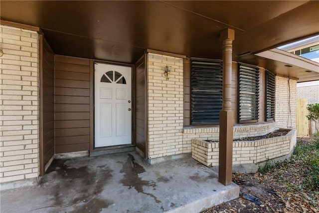 doorway to property with brick siding and covered porch