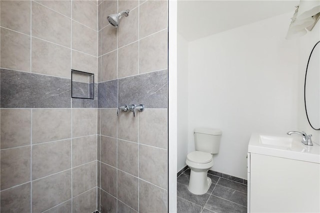 bathroom with tile patterned floors, tiled shower, toilet, and vanity