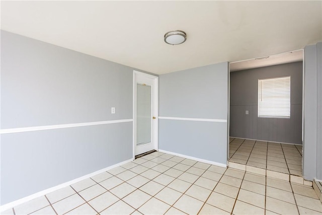 unfurnished room with light tile patterned floors and baseboards