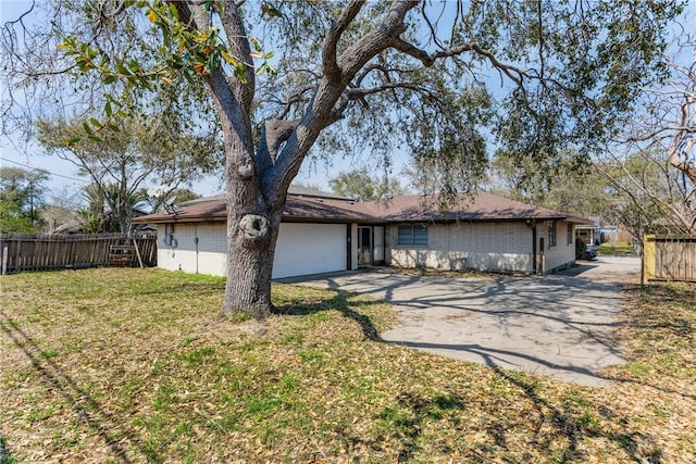 exterior space featuring concrete driveway, fence, and brick siding